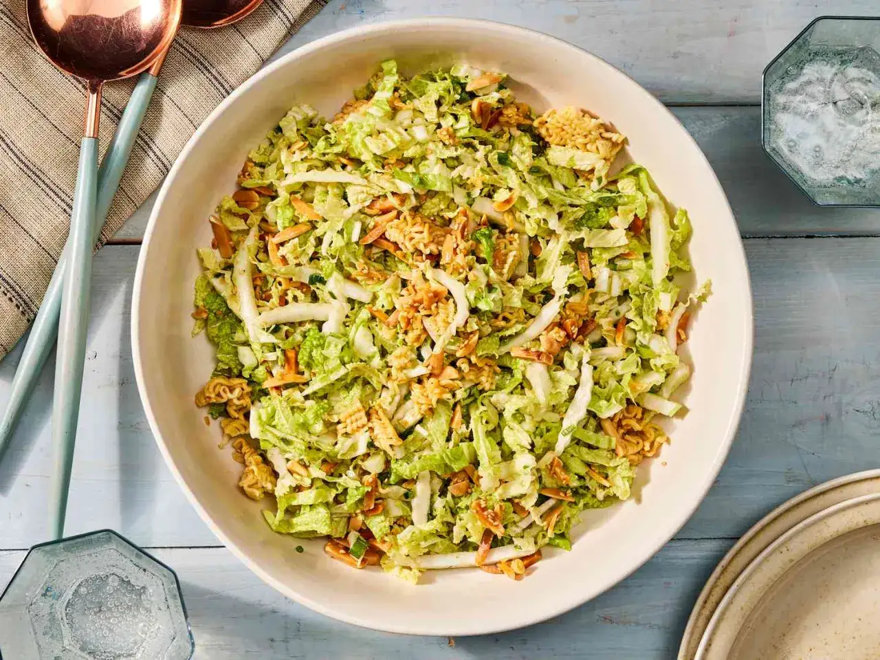Frischer Chinakohlsalat asiatisch mit knackigen Nudeln und Mandelsplittern, serviert in einer gro&szlig;en Sch&uuml;ssel.