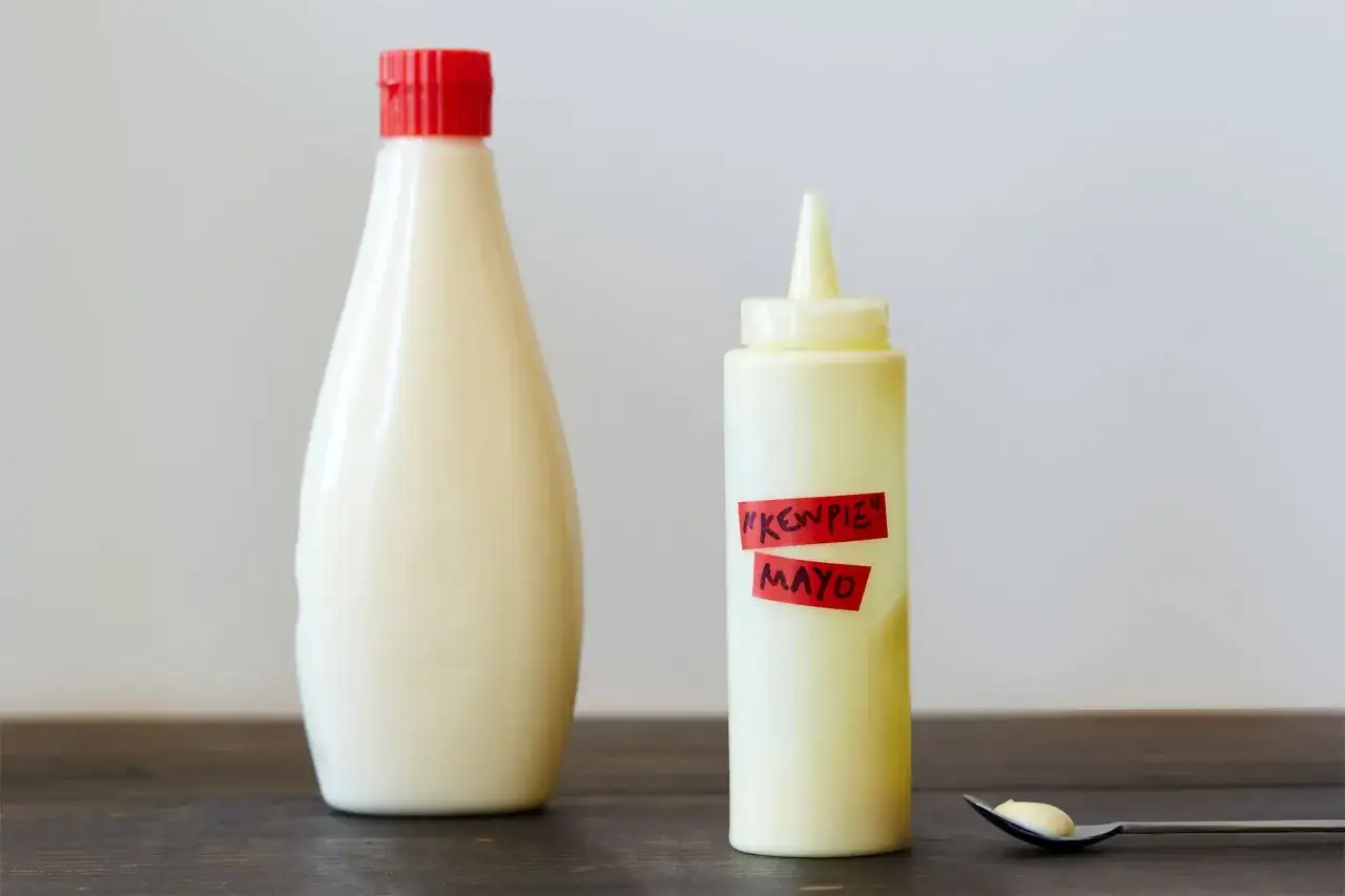 Zwei Mayonnaise-Flaschen, eine gro&szlig;e mit rotem Deckel und eine kleinere mit der Aufschrift 