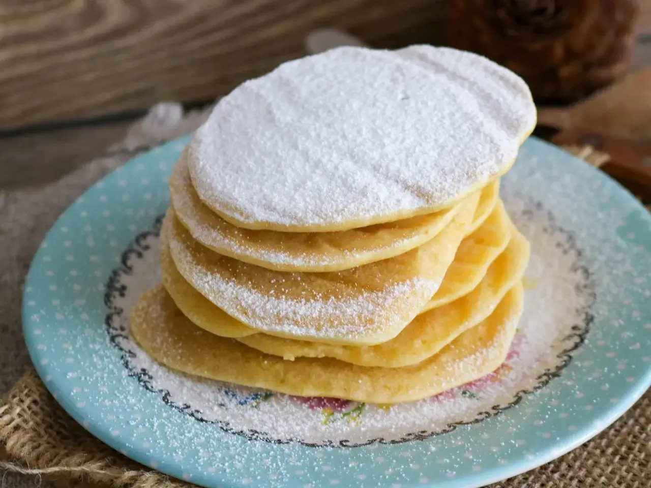 Ein Stapel Pfannkuchen, best&auml;ubt mit Puderzucker. Sie sehen aus, als w&auml;ren sie mit Reismehl gemacht, was ihnen eine leichte Textur verleiht.