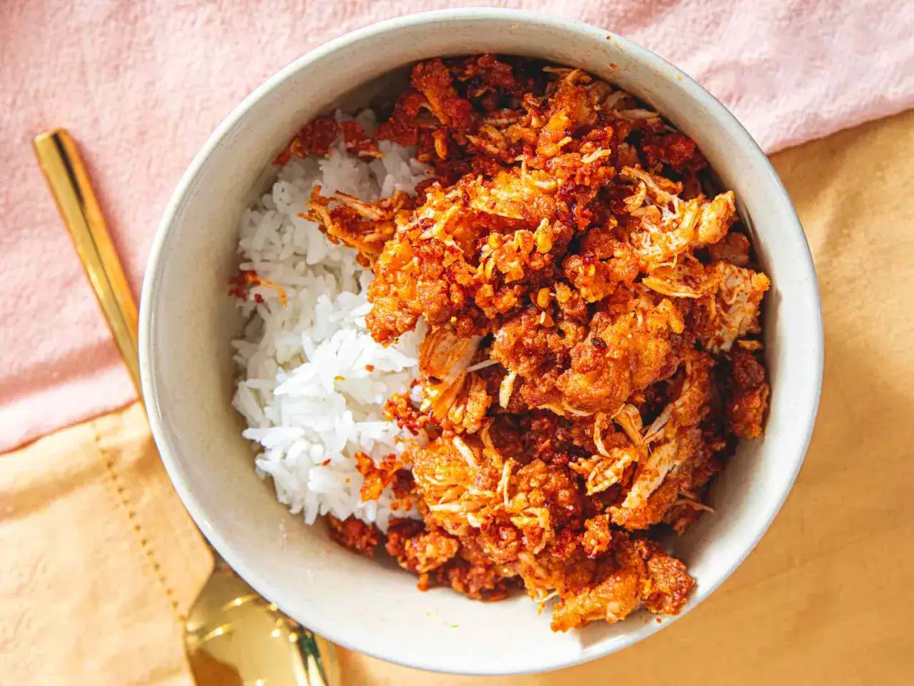 Sch&uuml;ssel mit wei&szlig;em Reis und w&uuml;rzigem H&auml;hnchen-Topping. Perfekt, wenn man sich fragt, wie lange muss reis kochen f&uuml;r ein schnelles, leckeres Essen.