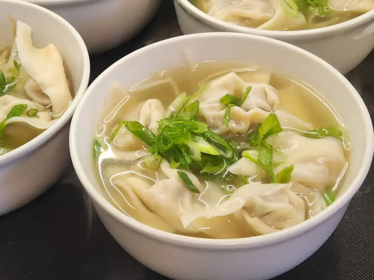 Sch&uuml;ssel mit dampfender Wan-Tan-Suppe, garniert mit Fr&uuml;hlingszwiebeln.