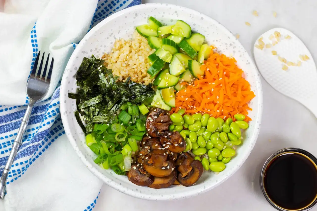 Bunter Poke Bowl mit Reis, Edamame, Karotten, Gurken, Nori und Pilzen, verfeinert mit einem Hauch von Sushi-Essig.