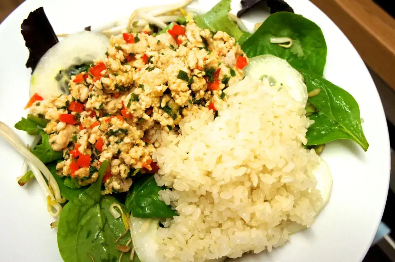 Laab Ped: Hackfleischsalat mit Reis, Gurkenscheiben, Sprossen und Spinat.