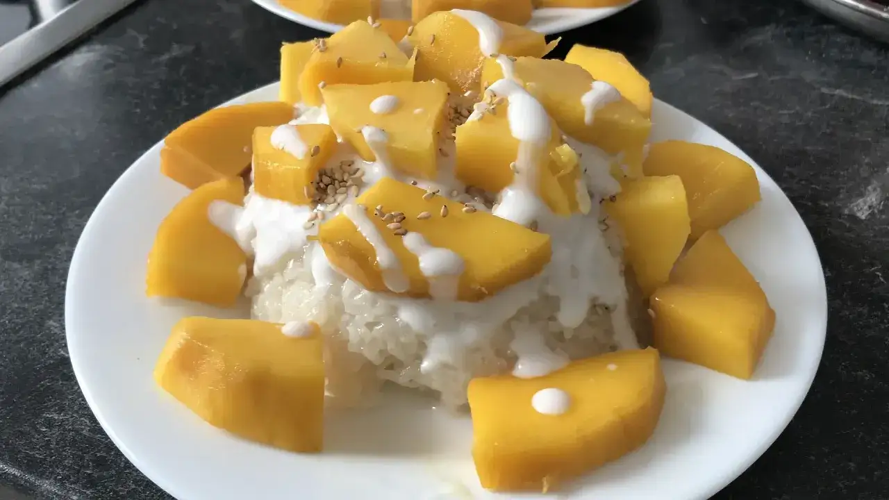 Süßer Klebreis mit Mango und Kokosmilch, bestreut mit Sesam. Ein köstlicher Bao Fan, der zum Genießen einlädt.