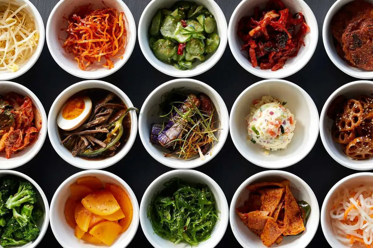 Vielfalt an koreanischen Banchan-Rezepten: Kimchi, eingelegte Gurken, Lotuswurzel und mehr in kleinen Schalen angerichtet.