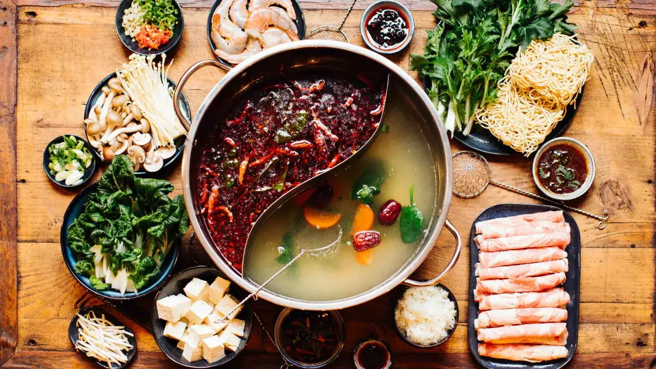 Ein köstlicher chinesischer Eintopf mit zwei Brühen, Garnelen, Pilzen, Gemüse, Tofu, Nudeln und dünn geschnittenem Fleisch.