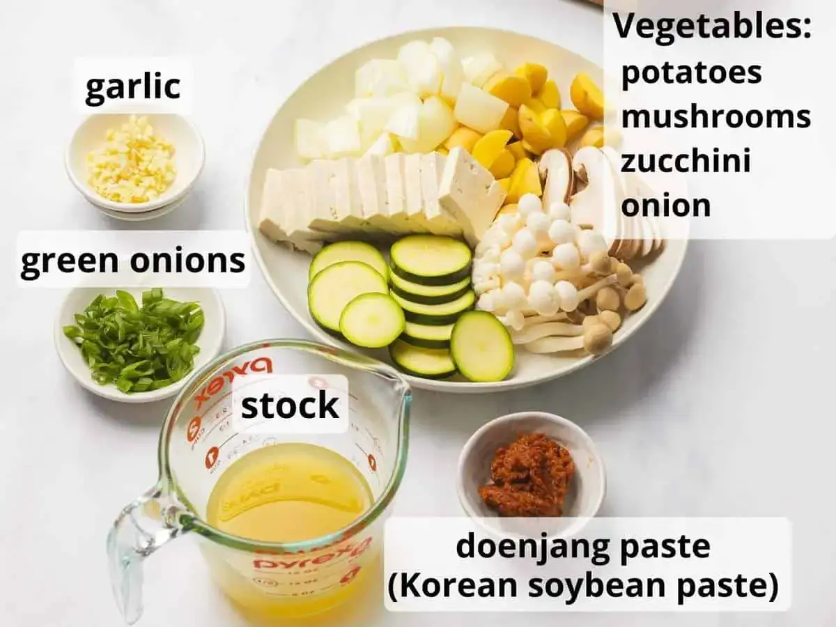 Zutaten f&uuml;r Doenjang Suppe: gew&uuml;rfeltes Gem&uuml;se (Kartoffeln, Zucchini, Pilze, Zwiebeln), Tofu, Knoblauch, Fr&uuml;hlingszwiebeln, Br&uuml;he und Doenjang Paste.