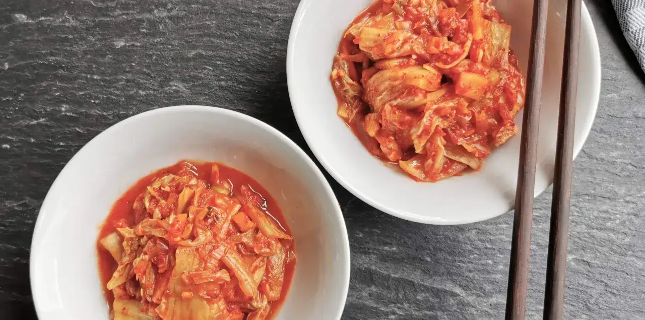 Zwei Schalen mit w&uuml;rzigem Kimchi, bereit f&uuml;r ein k&ouml;stliches Kimchi-Rezept. St&auml;bchen liegen daneben.